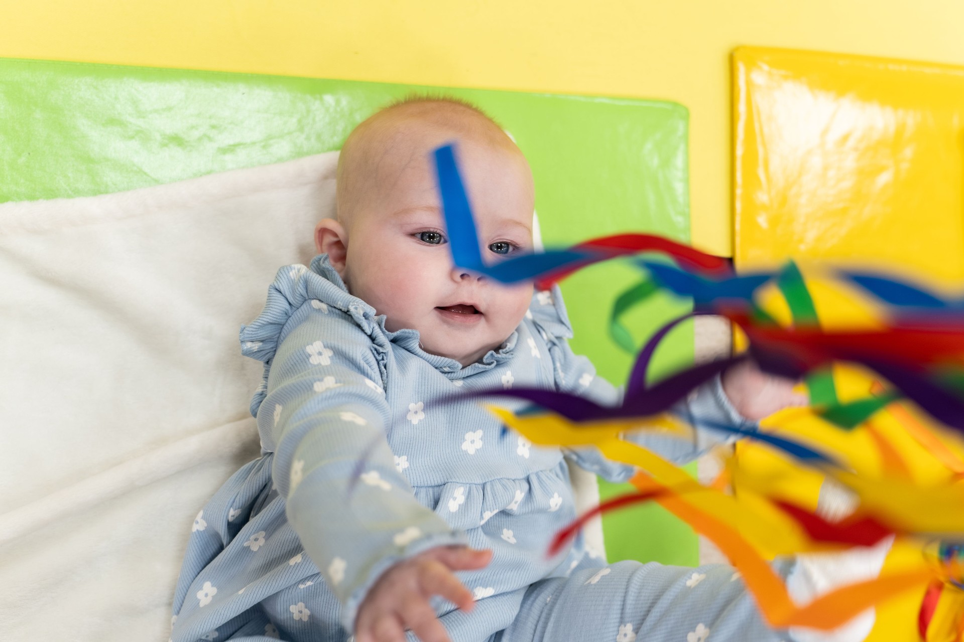 A baby exploring colourful ribbons during a Baby Sensory activity
